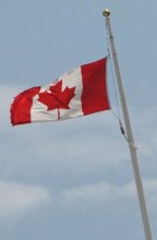 The canadian Flag flies against a blue sky