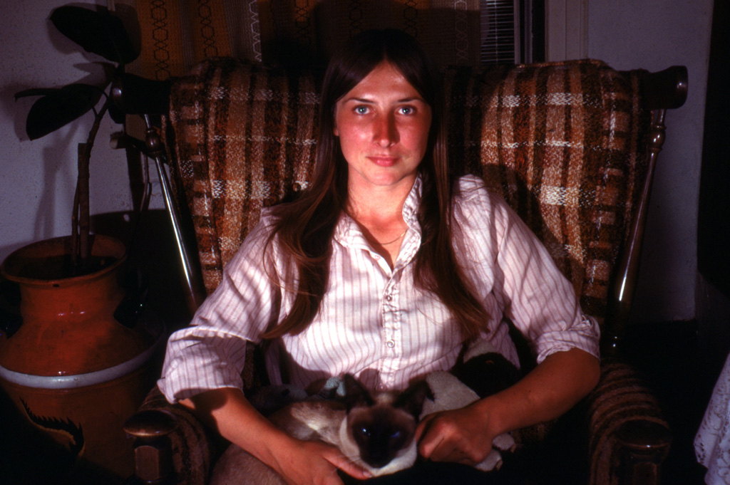 Mid twenties aged Lynda sits on her comfy chair with her favorite pet cat, Poukie installed in her lap